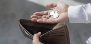 A imagem mostra uma pessoa segurando uma carteira vazia e moedas para representar que as tarifas aumentarão inflação.