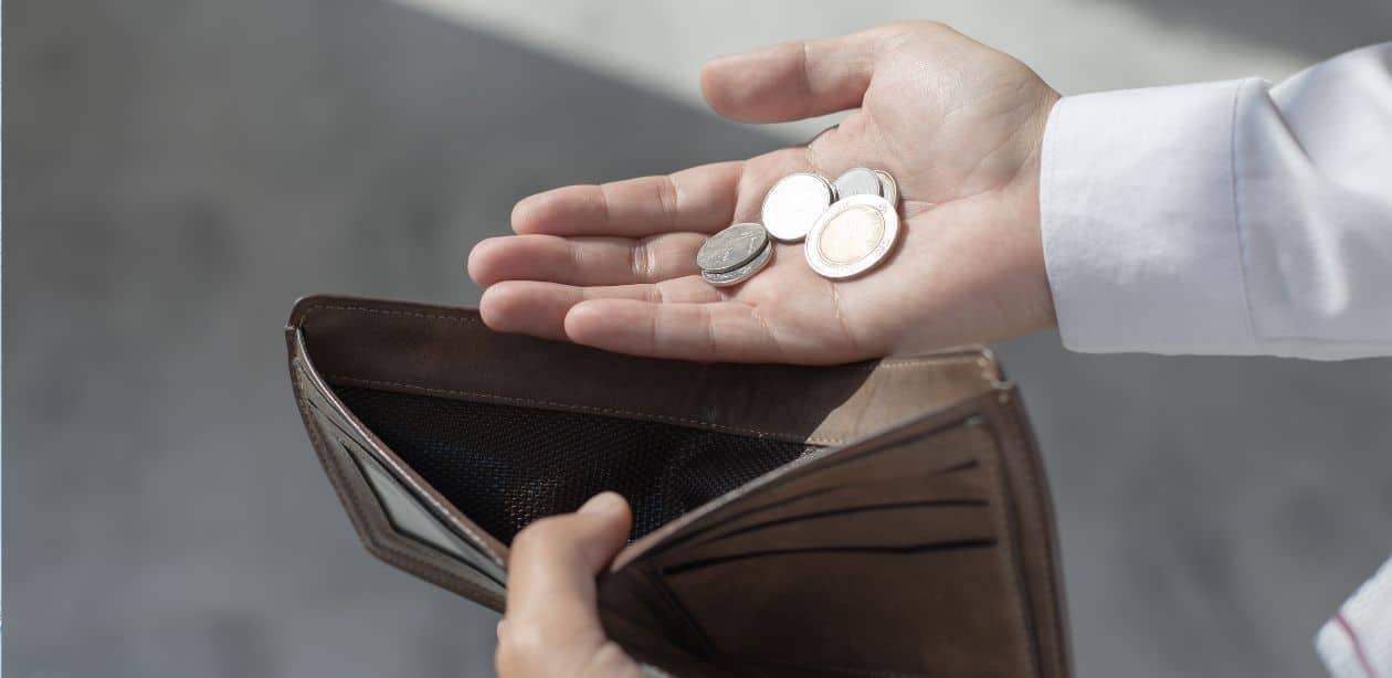 A imagem mostra uma pessoa segurando uma carteira vazia e moedas para representar que as tarifas aumentarão inflação.