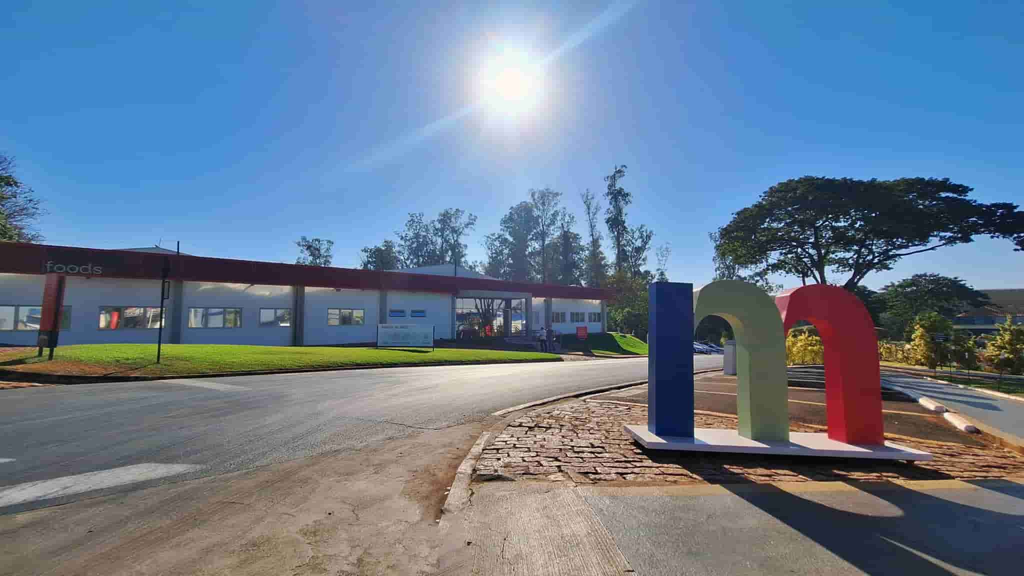 Fachada da unidade industrial da Minerva Foods em dia ensolarado, destacando escultura com logomarca colorida — imagem ilustrativa da emissão de CRA da Minerva em 2025.