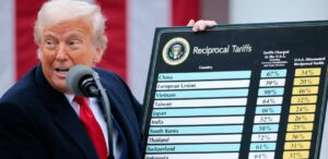 Donald Trump segurando um quadro com informações sobre tarifas recíprocas entre países, com destaque para dados de tarifas cobradas à EUA.