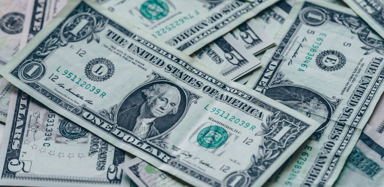 Cédulas de dólar americano sobrepostas, representando a alta da cotação do dólar hoje.