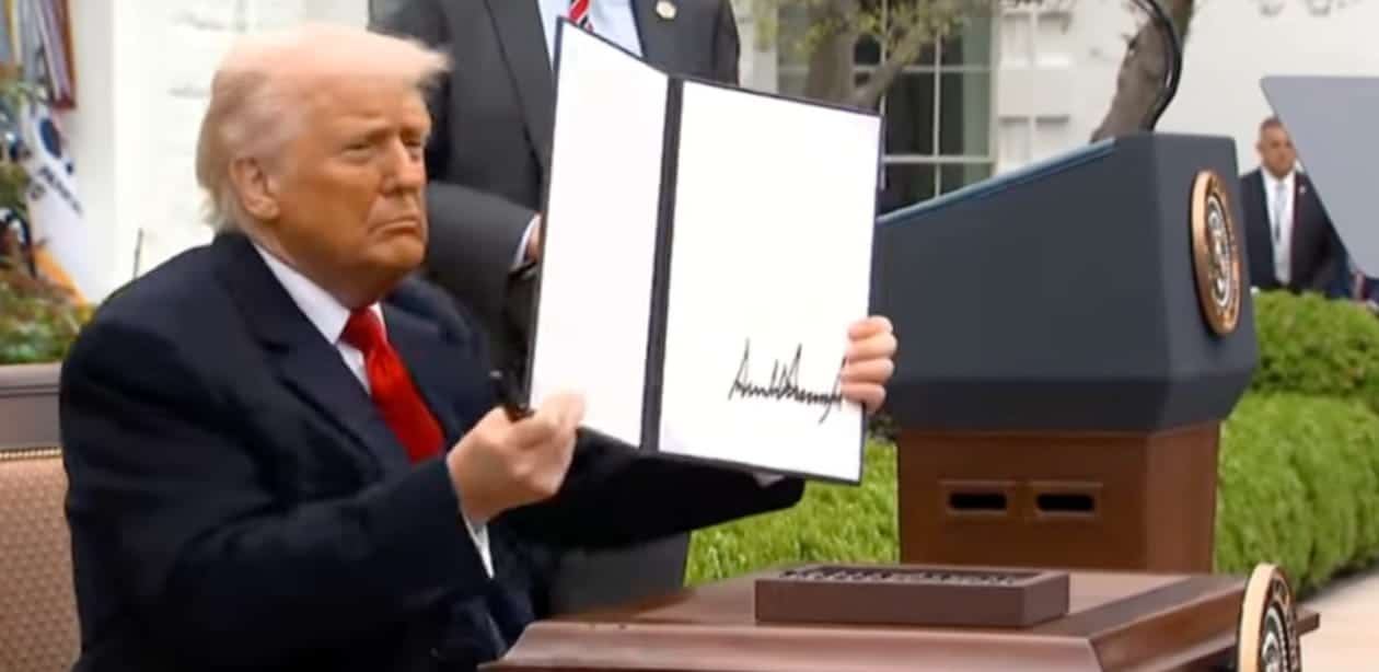 Donald Trump anuncia tarifa adicional contra China segurando documento oficial durante cerimônia.