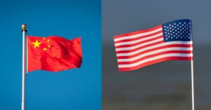 A imagem mostra as bandeiras dos EUA e China para representar que os EUA recuam e reduzem tarifas sobre importações da China