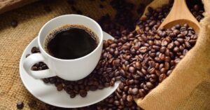 A imagem mostra uma xícara de café com grãos para representar o café impróprio para consumo