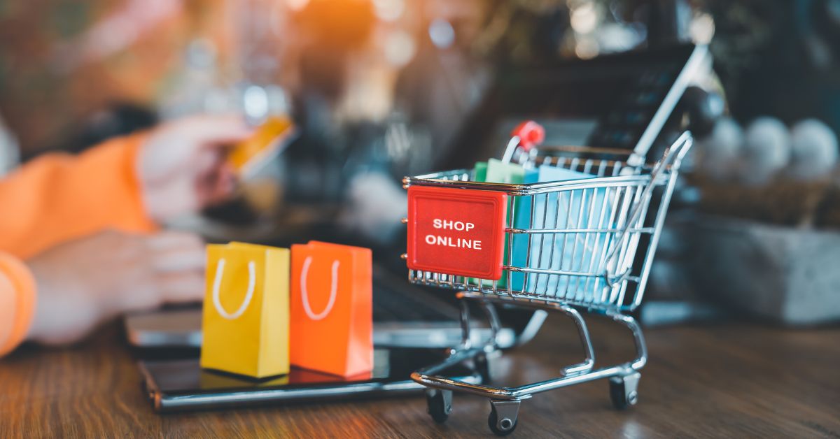 A imagem mostra um carrinho de compras em cima de um notebook para representar que a Anatel fiscaliza e apreende produtos