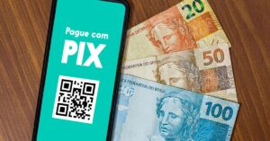 A imagem mostra dinheiro e um celular com um qr code para Pix como garantia