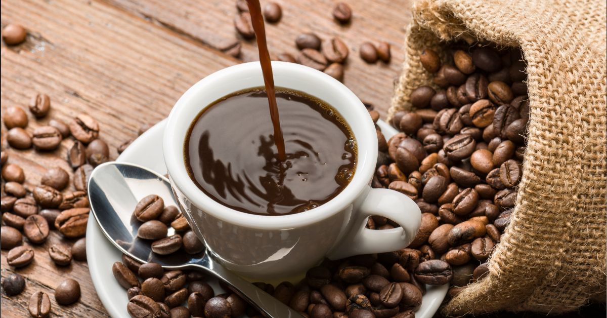 A imagem mostra uma xícara de café e grão para representar a queda na safra de café