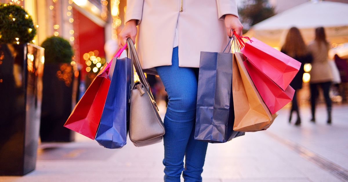 A imagem mostra uma mulher segurando sacolas de compras para representar as vendas do Dia das Mães