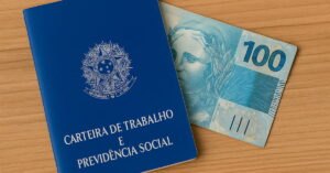 Carteira de Trabalho azul ao lado de uma nota de 100 reais, simbolizando o Consignado CLT e o crédito para trabalhadores formais.