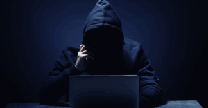 Hacker encapuzado diante de notebook simboliza empresas expostas a ataques cibernéticos no Brasil.