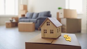 Casa em miniatura sobre caixa de mudança representa o aluguel comercial em maio de 2025