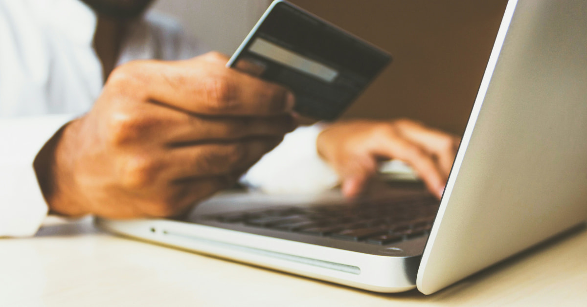Pessoa segura carteira e celular com tela de banco online, representando tentativas de fraude em bancos no ambiente digital