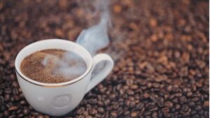 Xícara de café fumegante sobre grãos torrados – símbolo da Denominação de Origem para café do Paraná.