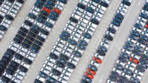 Imagem aérea mostra centenas de carros novos estacionados em pátio industrial, simbolizando o avanço das exportações de veículos no Brasil em 2025.