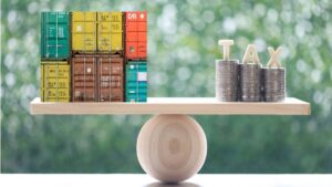 Balança entre contêineres e moedas representa a Lei da Reciprocidade Econômica