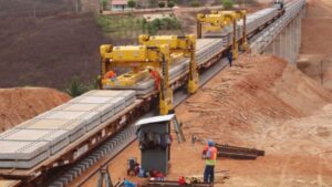 Obras ferroviárias em andamento em região semiárida do Ceará, com máquinas e trilhos sendo assentados.