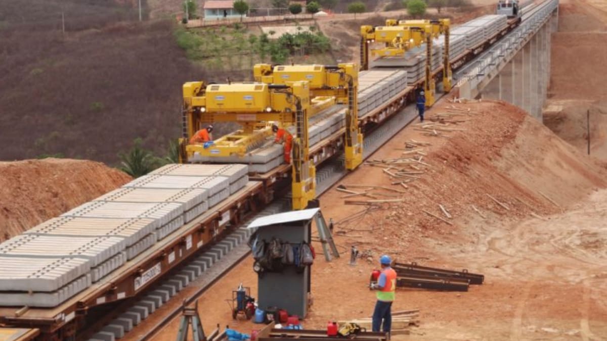 Obras ferroviárias em andamento em região semiárida do Ceará, com máquinas e trilhos sendo assentados.
