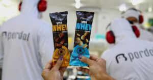 Picolé com Whey da Pardal nos sabores chocolate e amendoim sendo apresentados em ambiente de fábrica