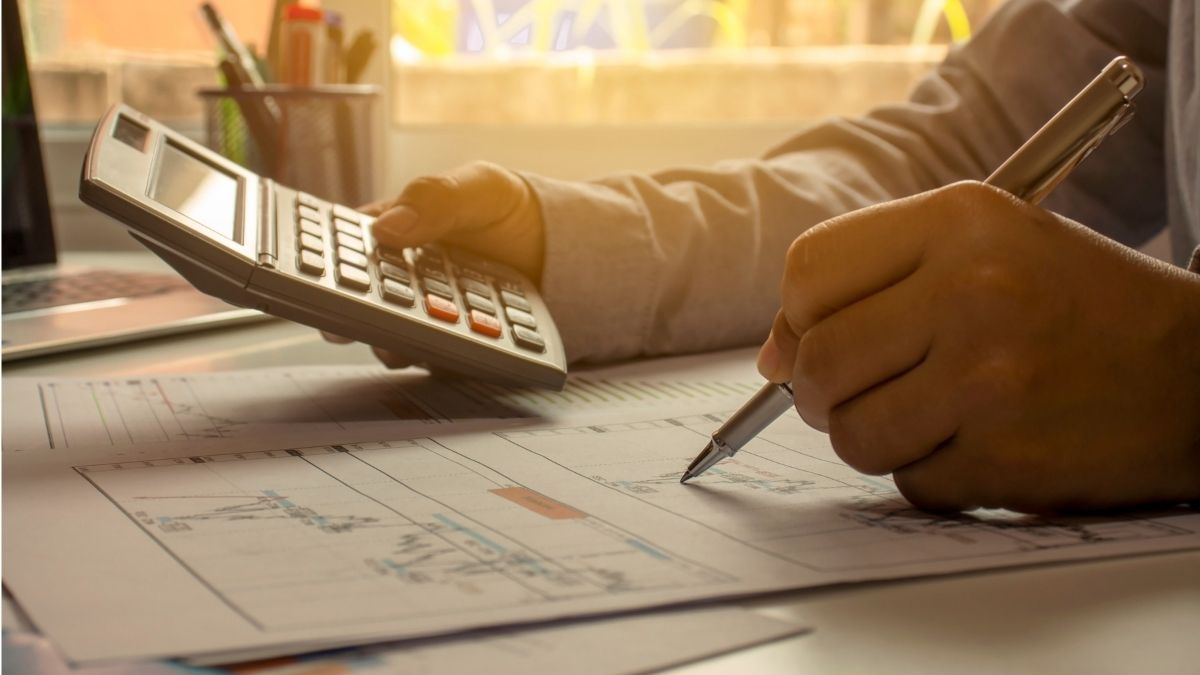 Pessoa utilizando calculadora e planilha para entender como economizar dinheiro em 2025.