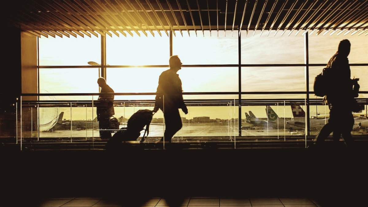 movimentação de passageiros nos aeroportos durante o amanhecer, com viajantes circulando e aviões ao fundo