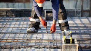 Empregos na construção civil em agosto, trabalhador em obra com estrutura de ferro