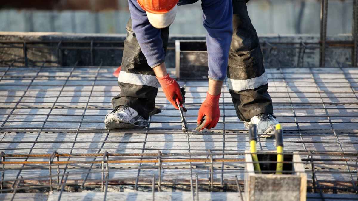 Empregos na construção civil em agosto, trabalhador em obra com estrutura de ferro