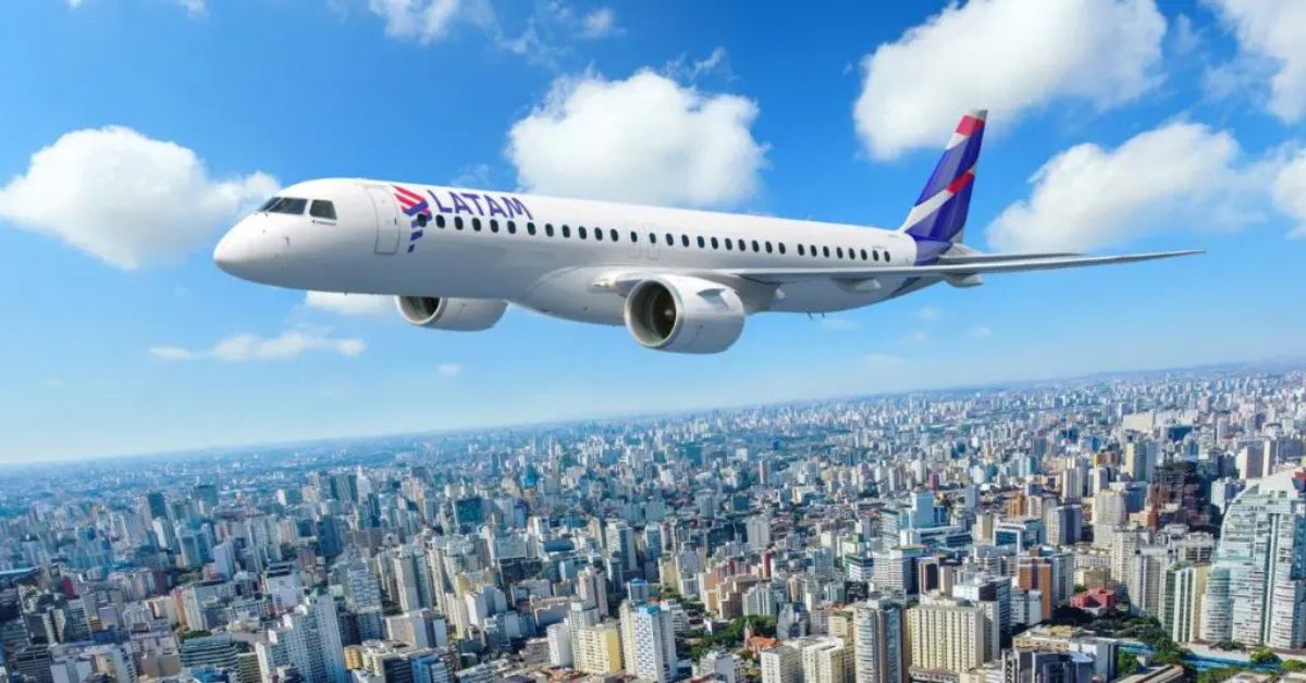 Avião Embraer Latam E195-E2 sobrevoa cidade com céu azul