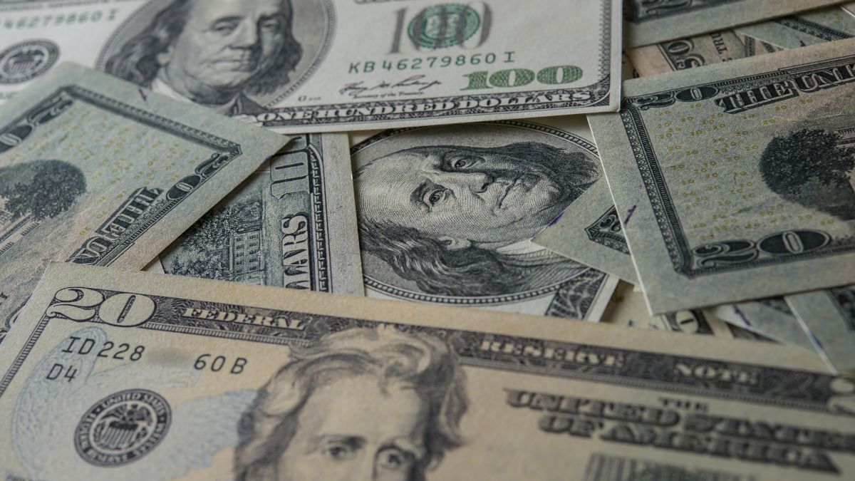 Notas de dólar espalhadas, ilustrando a cotação do dólar hoje em alta no mercado financeiro.