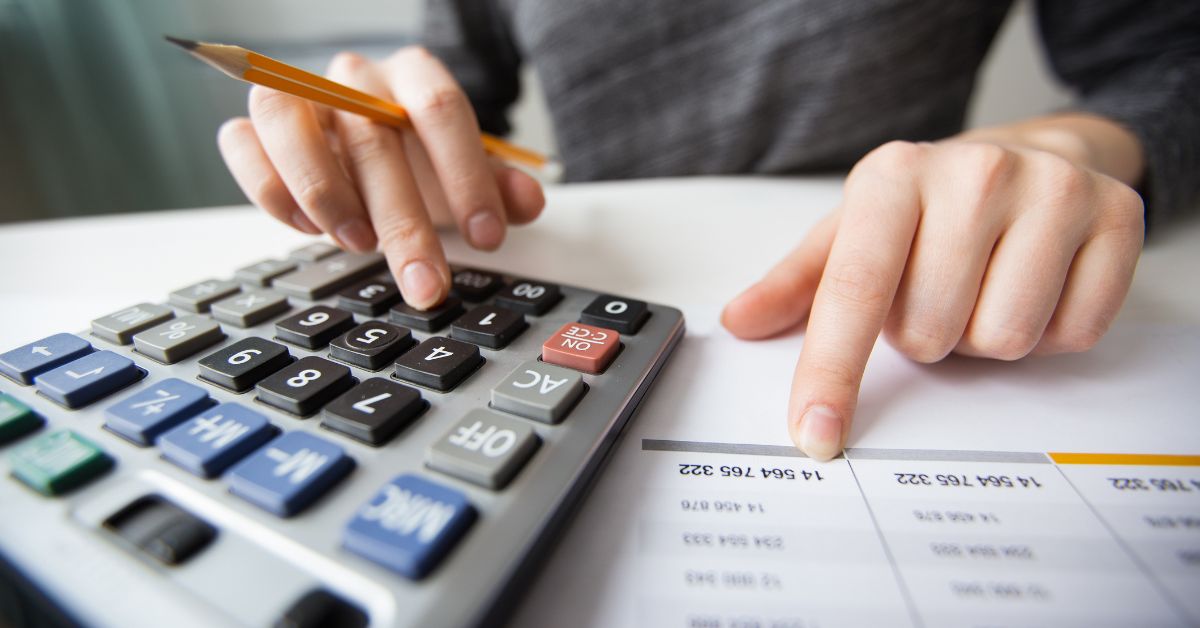 Pessoa faz cálculos financeiros com calculadora e planilha de impostos.