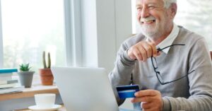 Idoso utilizando notebook para movimentações financeiras —economia da longevidade