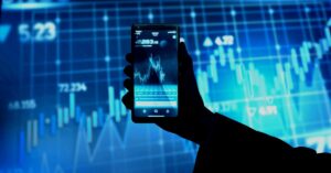 Pessoa segura um smartphone com gráfico financeiro na tela, simbolizando o uso de inteligência artificial em finanças pessoais e investimentos no Brasil.
