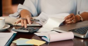 Pessoa calcula rendimentos e organiza documentos para declarar o Imposto de Renda para investidores.