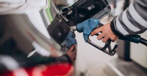 motorista abastece veículo em posto de combustíveis, ilustrando variação no preço da gasolina nas refinarias da Petrobras