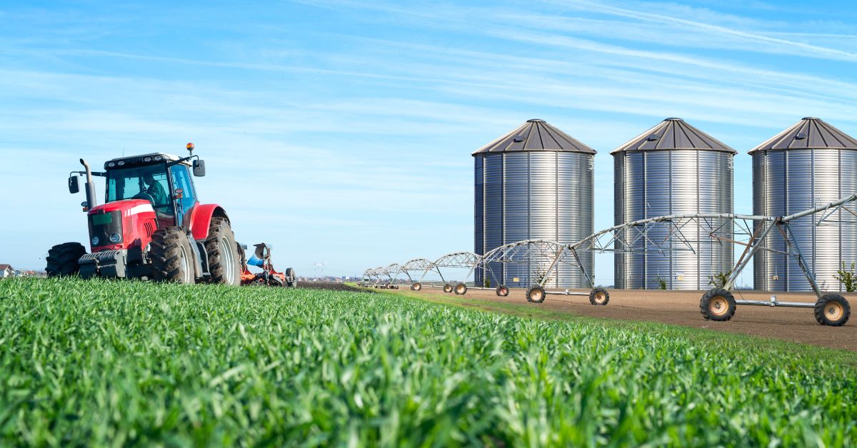 Produção agrícola 2025 no Brasil — trator em lavoura e silos metálicos no Centro-Oeste