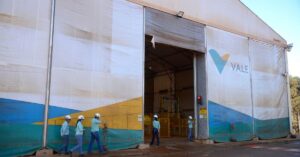 Resultados da Vale no 3T25: Funcionários da empresa em frente à unidade operacional, com logotipo visível na fachada.