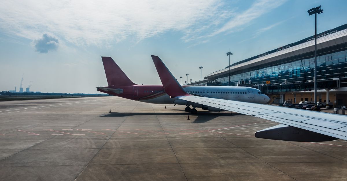 Aviões em pista de aeroporto brasileiro com terminal moderno, símbolo da menor tarifa aeroportuária do mundo segundo a Anac