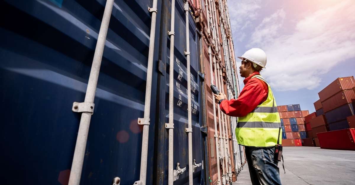 Trabalhador inspeciona contêineres em operação logística ligada ao crédito para exportação.