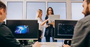 Zenstox vs corretores Tier-1: profissionais analisando gráficos e plataformas de investimento.