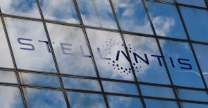 Fachada da Stellantis refletindo o céu, simbolizando o investimento da empresa nos EUA para recuperar participação de mercado.