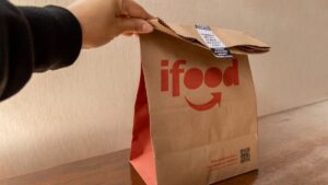 Imagem de uma pessoa segurando uma bolsa do iFood para ilustrar uma matéria jornalística sobre o iFood no BBB.