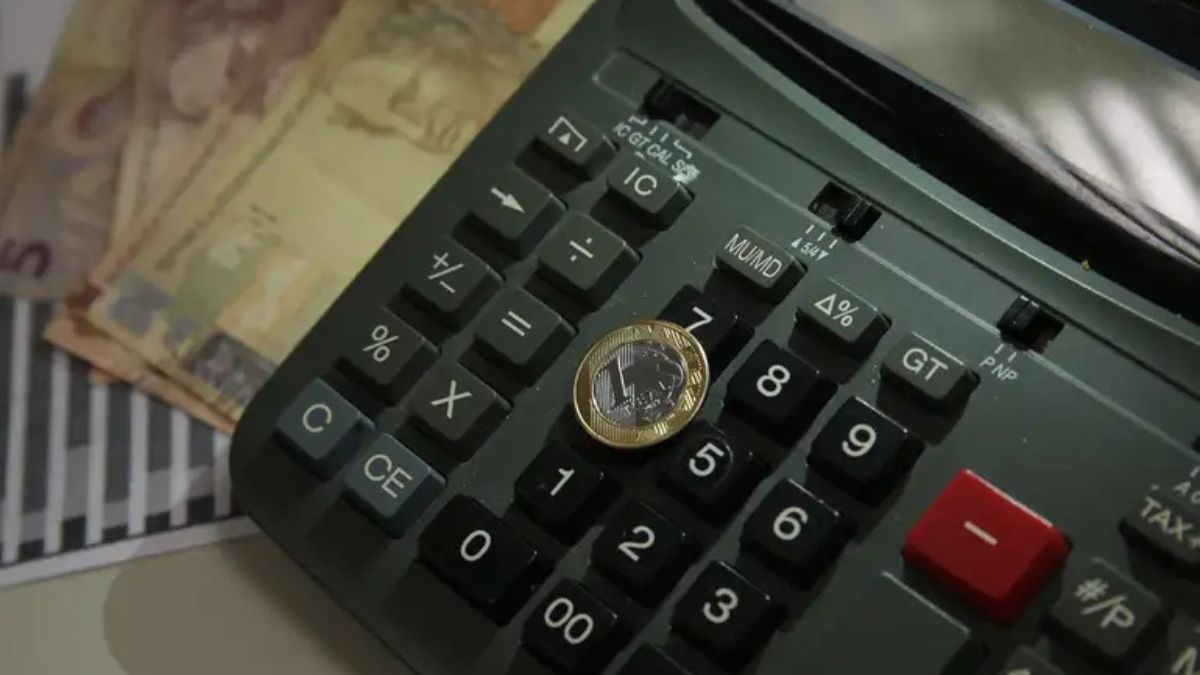 Imagem de uma calculadora com dinheiro para ilustrar uma matéria jornalística sobre a Inadimplência do Brasil.