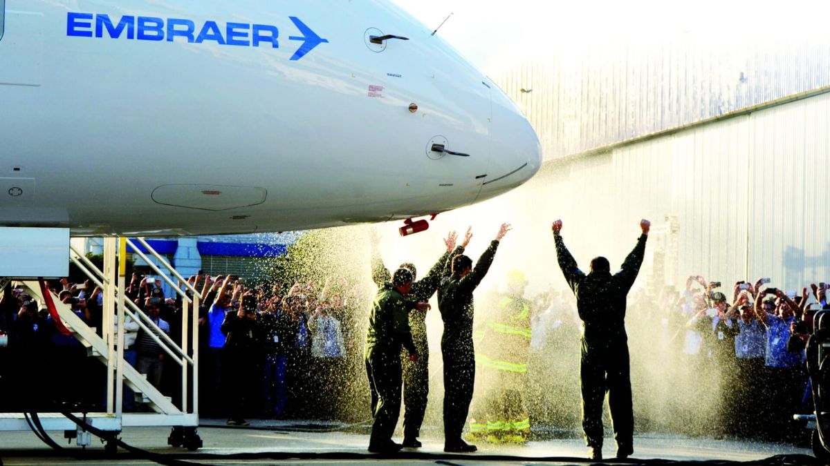Imagem de um avião da EMbraer com técnicos comemorando para ilustrar uma matéria jornalística sobre a Embraer e a Finnair.