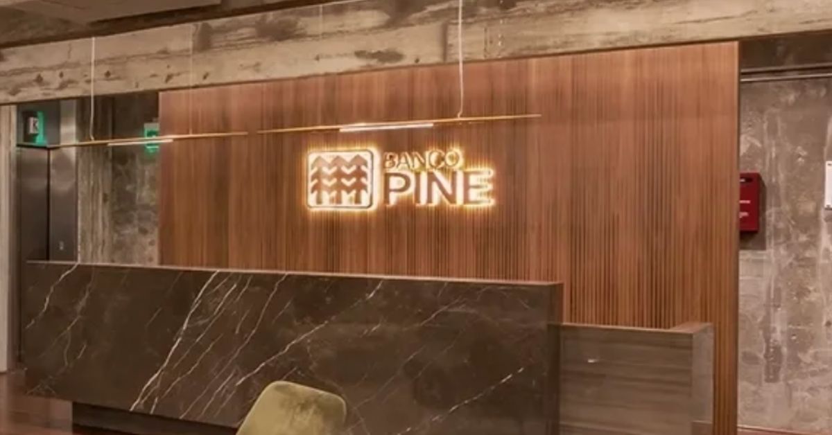 Interior da sede do Banco Pine com logotipo iluminado, destacando o desempenho das ações do Banco Pine na bolsa brasileira