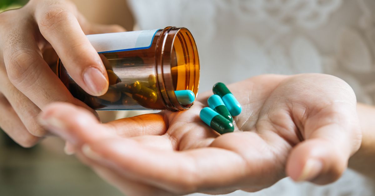 Pessoa segurando cápsulas de medicamento na mão após retirar de frasco, simbolizando futuro aumento no preço dos remédios