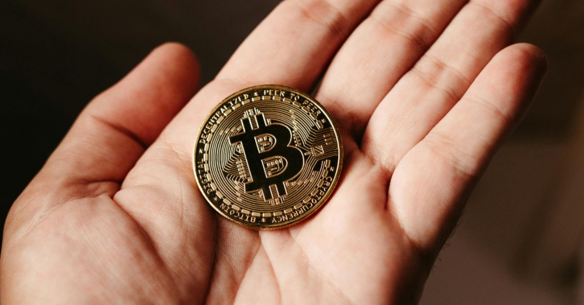 Moeda de Bitcoin sobre a mão, representando a valorização da criptomoeda no mercado