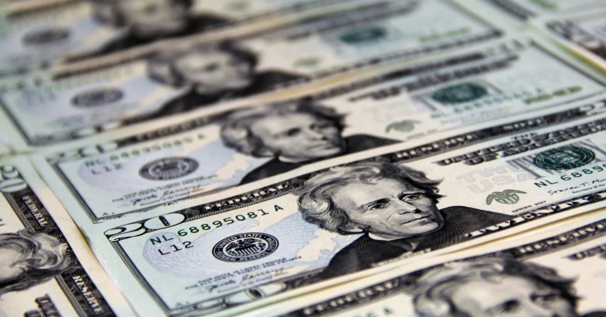 Notas de dólar americano dispostas em sequência, representando a queda da moeda frente ao real