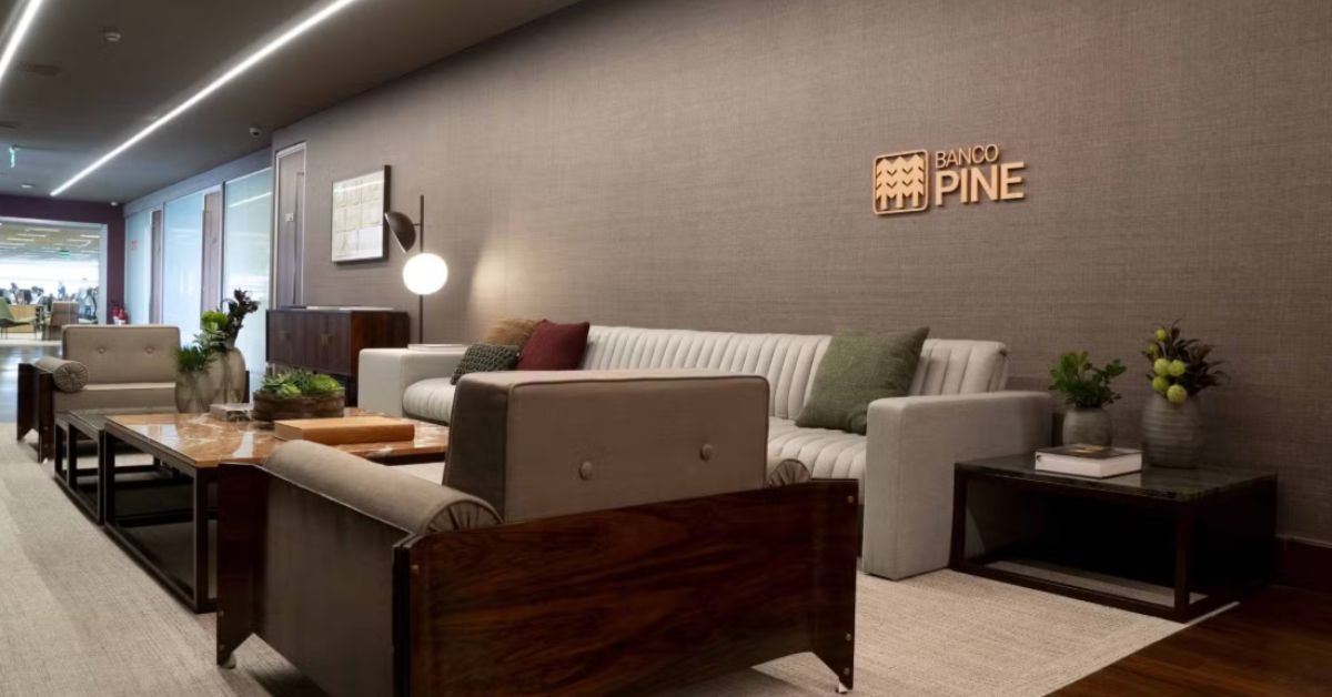 Interior do escritório do Banco Pine, com logo da instituição em destaque na parede