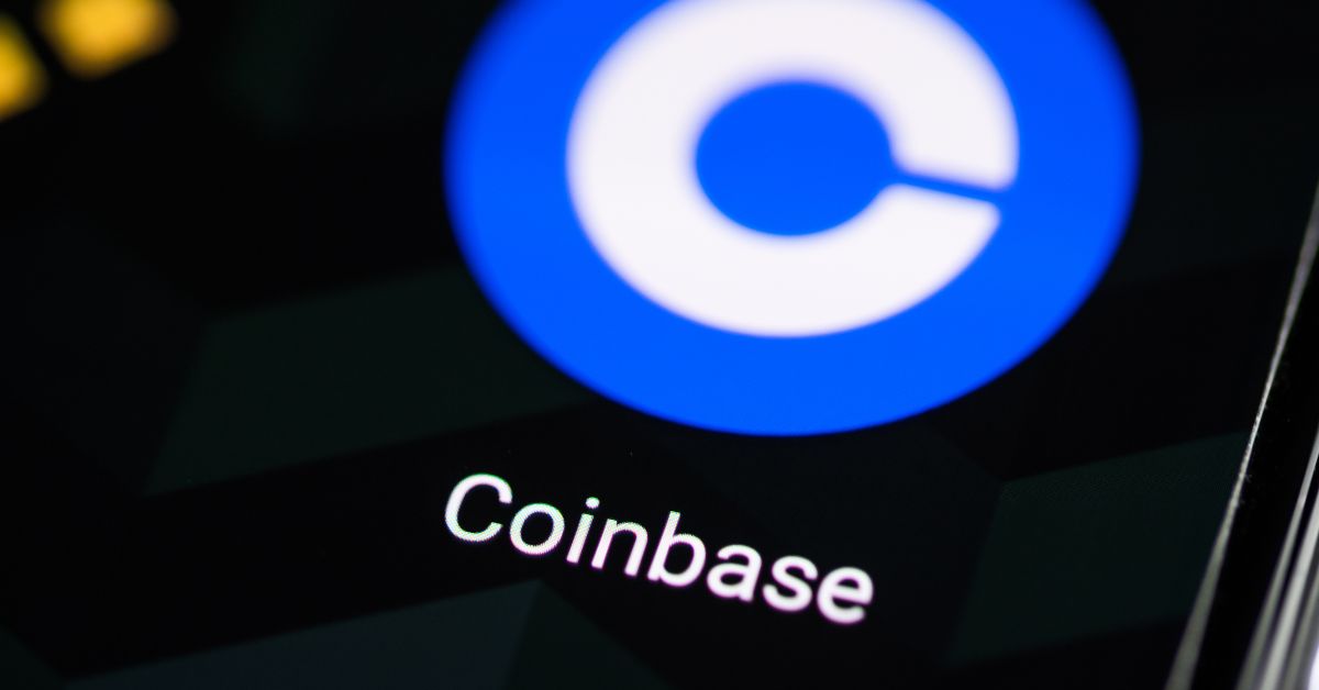 logo da Coinbase em tela de celular após anúncio de demissões e reestruturação com foco em IA