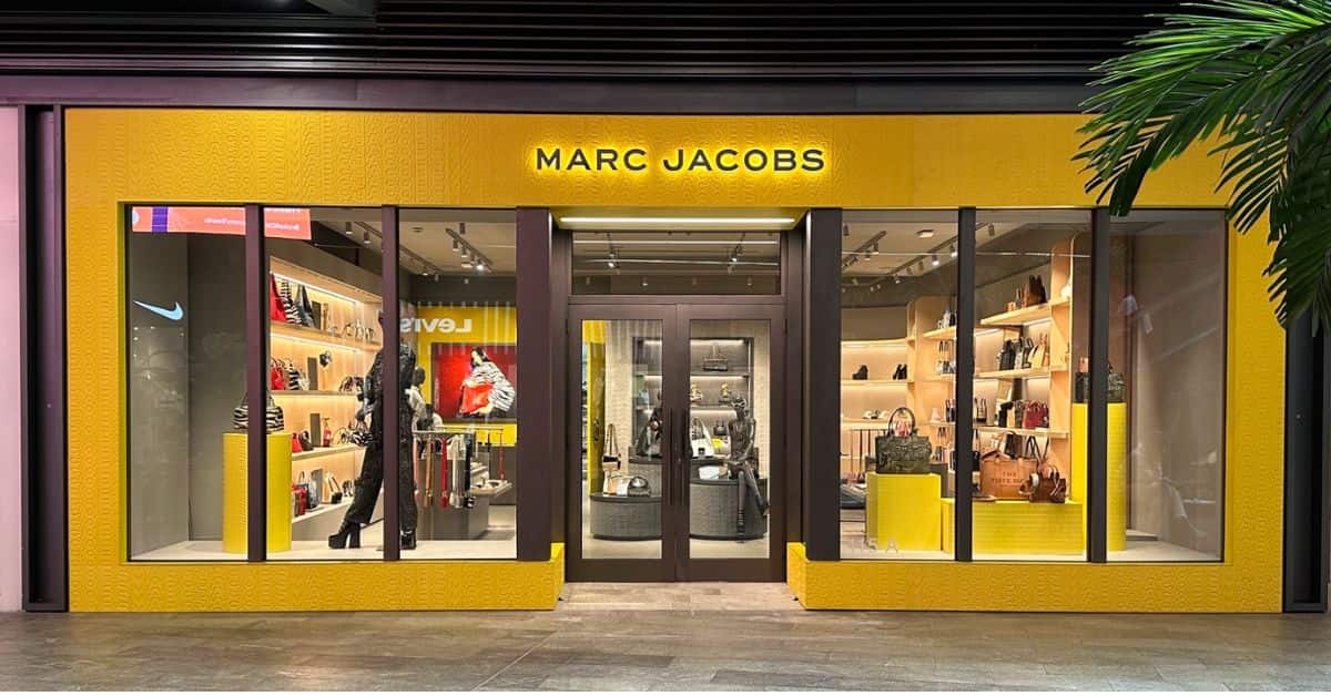 Fachada de loja da Marc Jacobs com vitrine iluminada e produtos expostos após anúncio de venda da marca pela LVMH.