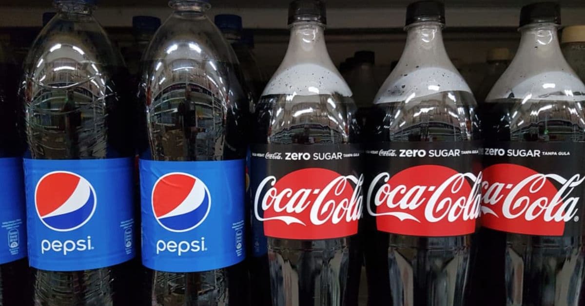Garrafas de Pepsi e Coca-Cola lado a lado em prateleira, com destaque para versão sem açúcar